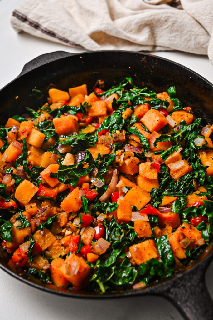 Butternut squash, red bell pepper, and kale in a skillet.