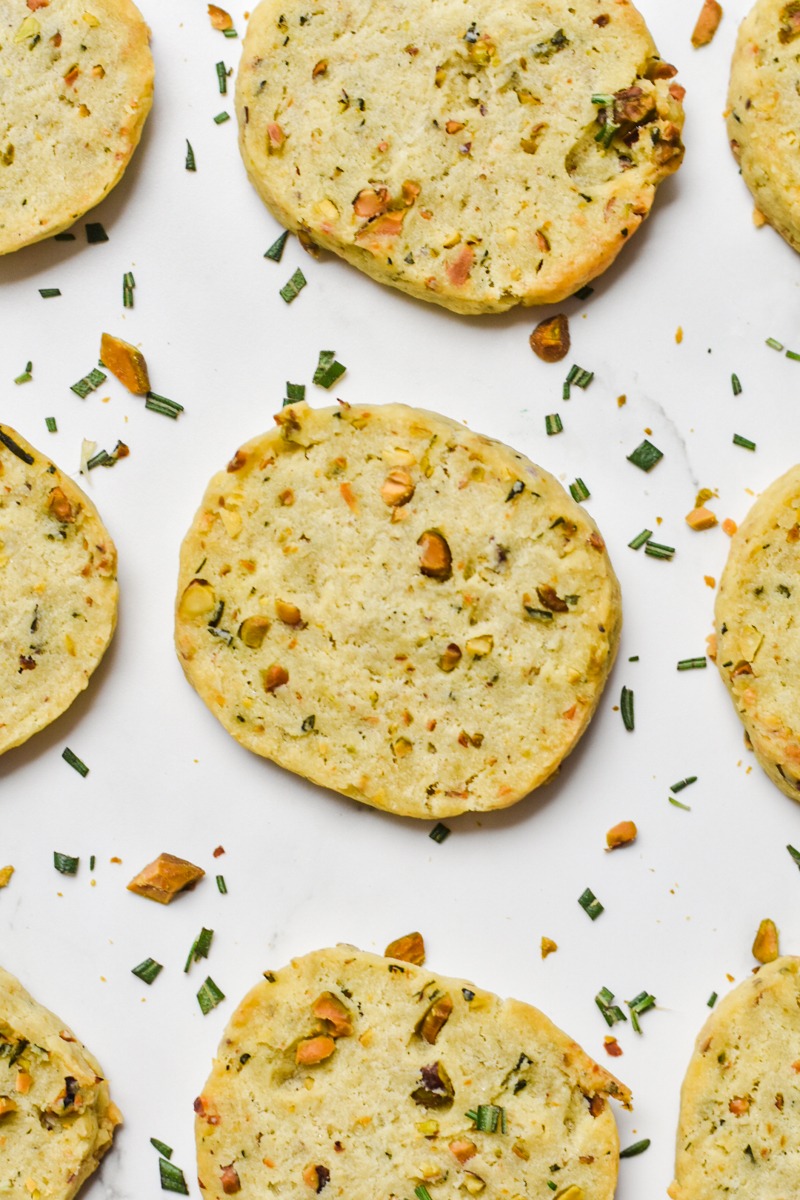 Close up of parmesan rosemary shortbread cookies lined up on a counter.