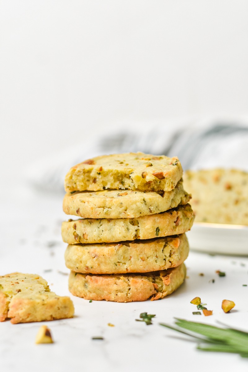 Savory parmesan rosemary and pistachio shortbread cookies stacked on top of each other.