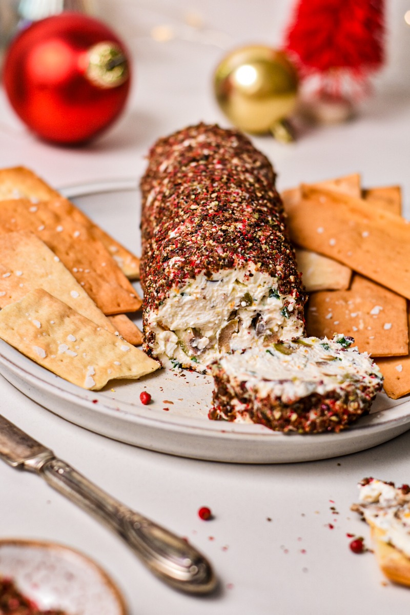 Olive and feta cheese log with a slice off the end and crackers on the side.
