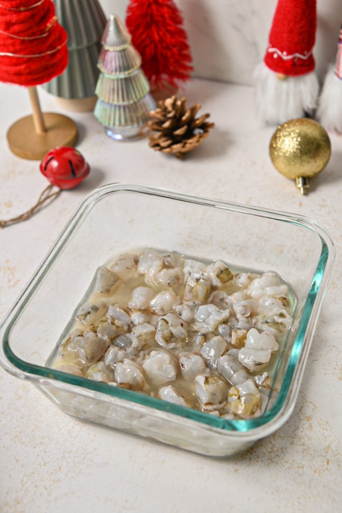Chopped shrimp in citrus juice in a glass container.