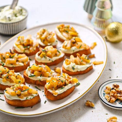Whipped gorgonzola crostini with pears on a serving platter.