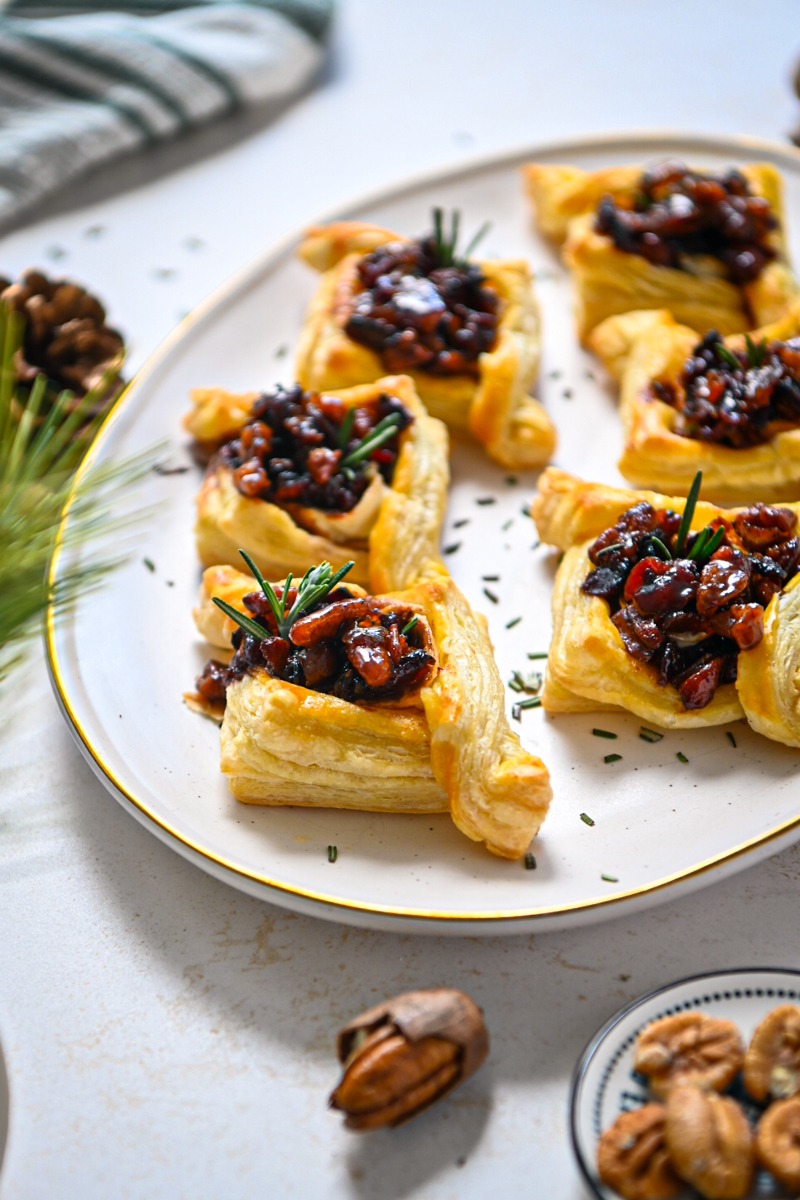 White serving platter with puff pastry brie bacon jam bites.