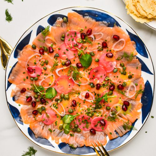 Smoked salmon carpaccio served on a white and blue plate.