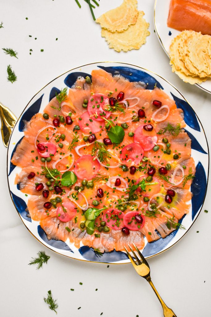 Smoked salmon carpaccio served on a white and blue plate.