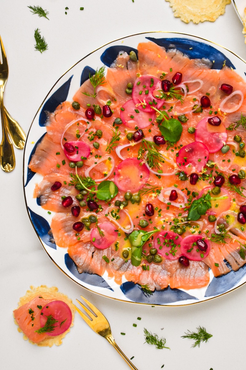 Smoked salmon carpaccio served on a plate with one piece served on a cracker.