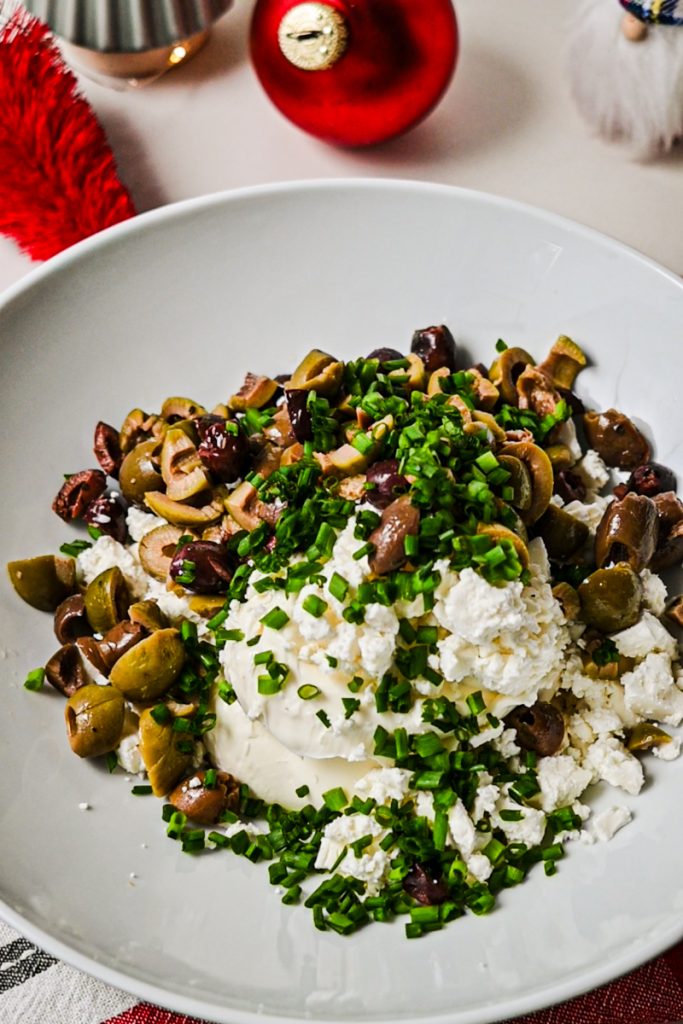 Olives and chives added to the cheese in a mixing bowl.
