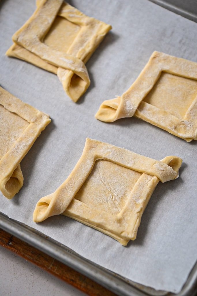 Puff pastry squares assembled on a sheet pan.