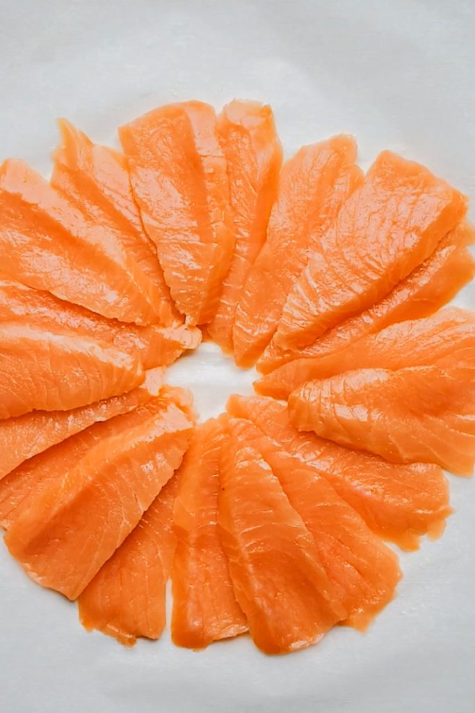 Smoked salmon pieces arranged in a circle on parchment paper.